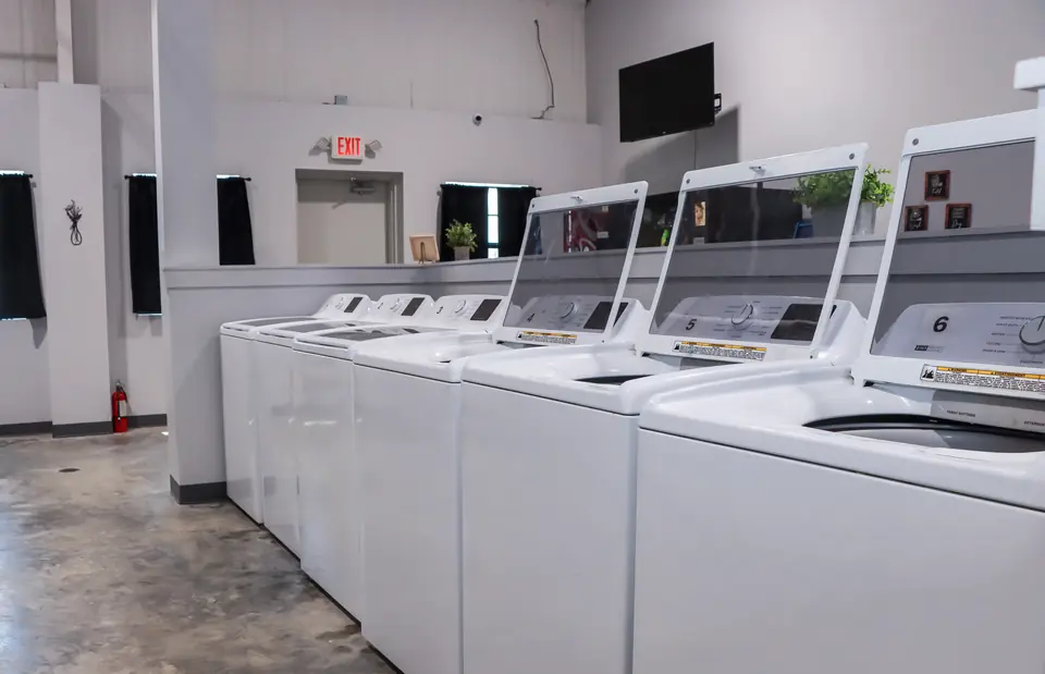 Row of numbered top-load washing machines in a shared laundry room
